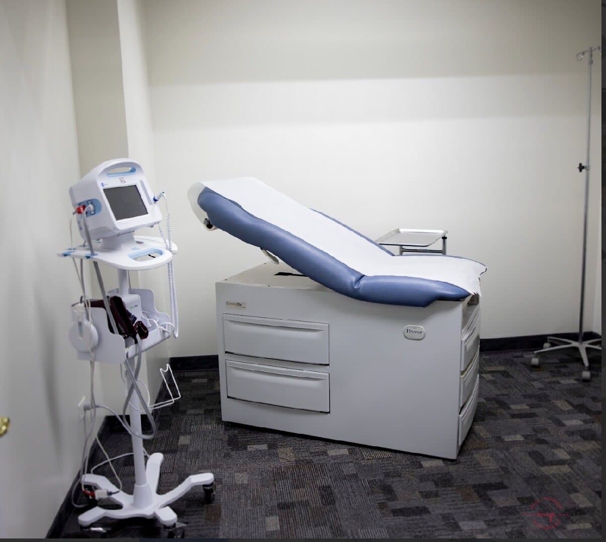 An exam room at Barrington Primary and Urgent Care, with an exam table and vitals monitor